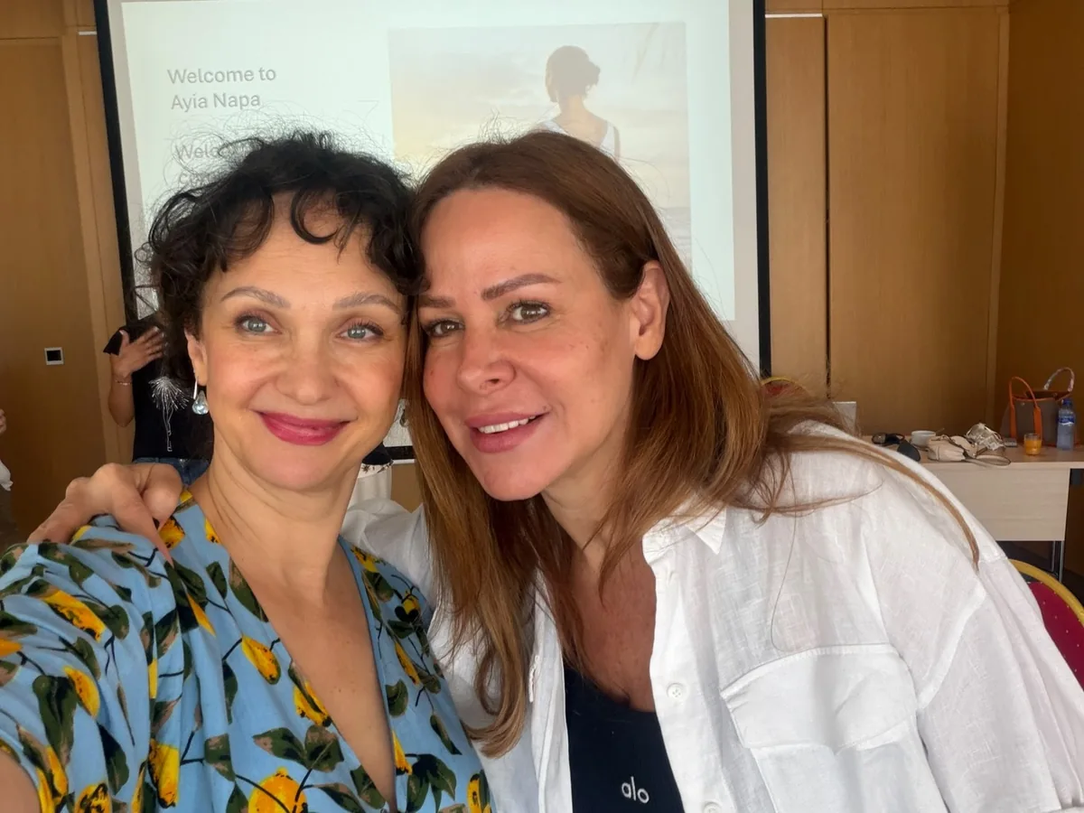 Două participante zâmbind, în sala de seminar